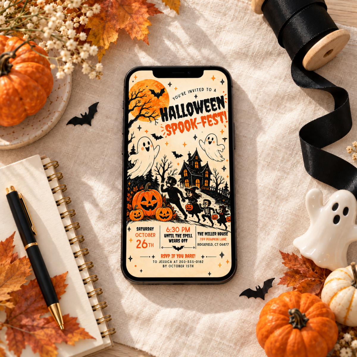 Spook-Fest Halloween invitation displayed on a phone beside autumn decorations