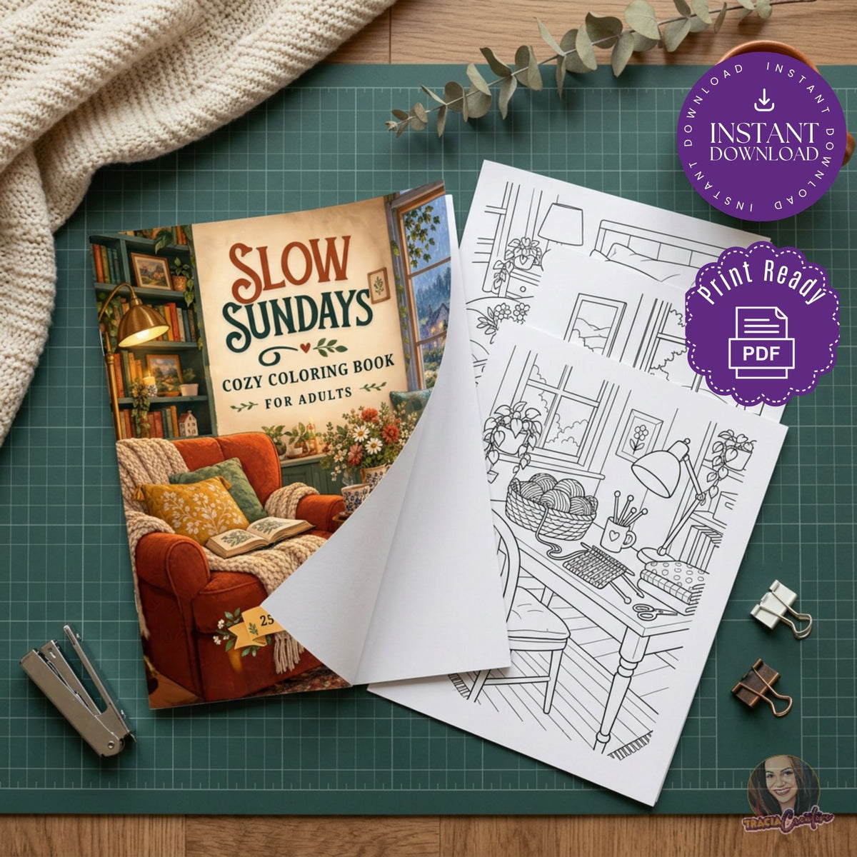A styled flat-lay of a cozy coloring book and its black-and-white interior coloring page on a green cutting mat, with a beige knit blanket, eucalyptus sprig, paper clips, and a stapler around it. Purple badges read 'Instant Download' and 'Print Ready'.